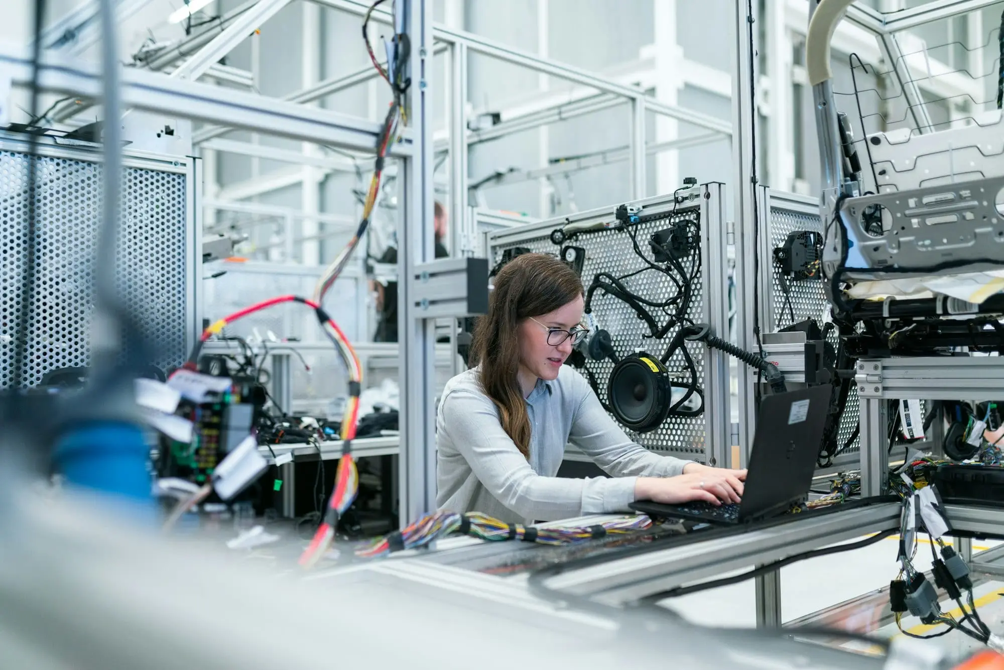 An engineer working at a laptop beside production machinery