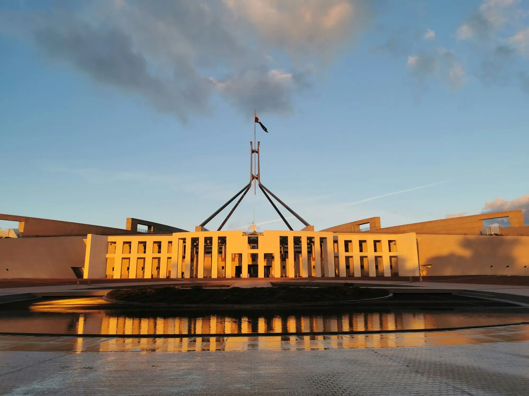 Parliament House in Canberra at dusk, with its flagpole over the roof