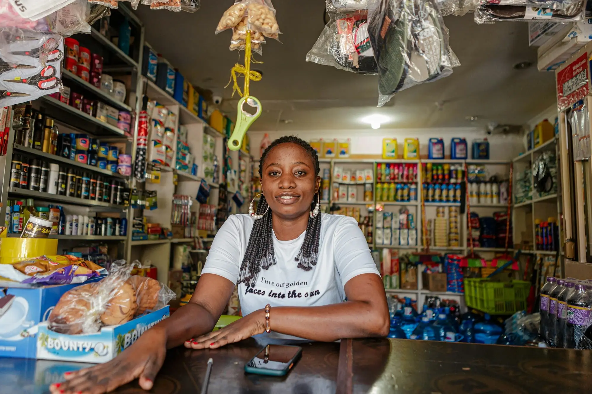 A shop owner leaning on the counter of her small general store